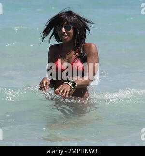 Alexandra Burke porte un bikini couleur pêche à la plage comme elle aime un autre jour au soleil. Tout en faisant une promenade sur la plage dans une robe longue rayée tendance Burke s'est arrêté pour ramasser des coquillages avant de prendre un plongeon dans l'eau de refroidissement. Plus tard, la chanteuse a montré ses multiples bracelets perlés comme elle a texté sur son unique téléphone cellulaire clouté. Miami Beach, Floride. 3/7/11 Banque D'Images