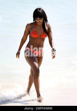 Alexandra Burke porte un bikini couleur pêche à la plage comme elle aime un autre jour au soleil. Tout en faisant une promenade sur la plage dans une robe longue rayée tendance Burke s'est arrêté pour ramasser des coquillages avant de prendre un plongeon dans l'eau de refroidissement. Plus tard, la chanteuse a montré ses multiples bracelets perlés comme elle a texté sur son unique téléphone cellulaire clouté. Miami Beach, Floride. 3/7/11 Banque D'Images