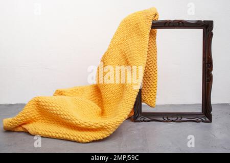 Couverture en crochet orange dévoilant un cadre en bois sur un comptoir en ciment gris, modèle de présentation de produit Banque D'Images