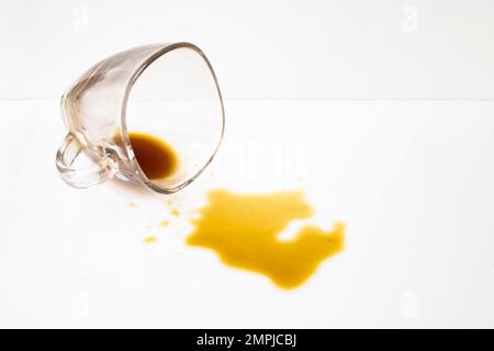 Le café s'est renversé dans une tasse en verre transparent sur fond blanc, mise au point douce en gros plan Banque D'Images