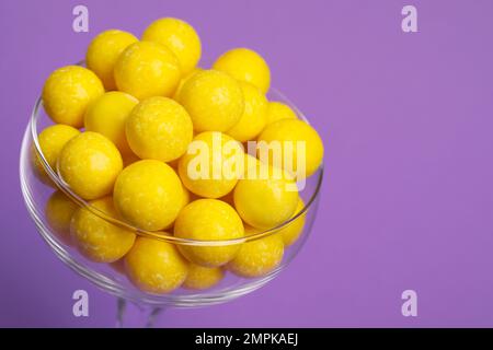 De savoureuses gommes à mâcher au citron en verre sur fond violet, gros plan Banque D'Images