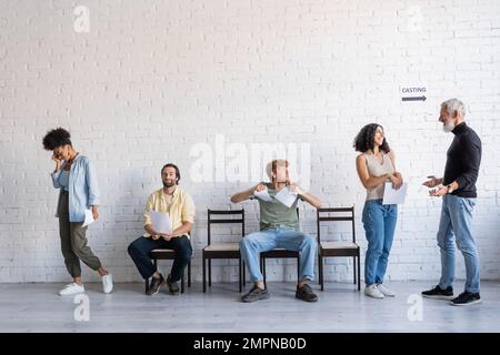 un producteur aux cheveux gris qui parle à une heureuse femme multiraciale proche de ceux qui cherchent un emploi multiethnique contrarié Banque D'Images