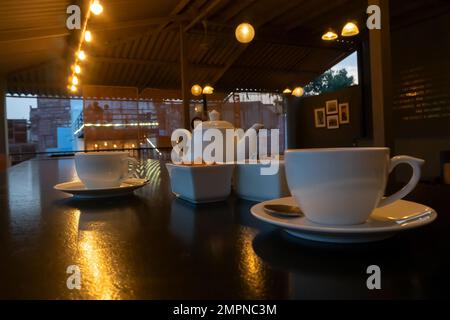 Belle vue intérieure du restaurant à Jodhpur Rajasthan, Inde. Tasses blanches, plats et théière avec reflet de lumières décorées sur la table brillante Banque D'Images