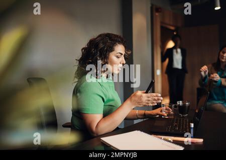 Vue latérale d'une femme d'affaires qui fait des gestes tout en discutant avec ses collègues au bureau Banque D'Images
