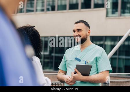Un professionnel de la santé qui tient un PC tablette et qui parle à une collègue féminine Banque D'Images
