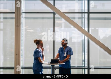 Un médecin de sexe masculin explique la collègue féminine au sujet d'un PC tablette à l'hôpital Banque D'Images