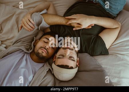 Vue en grand angle du couple gay dormant sur le lit à la maison Banque D'Images