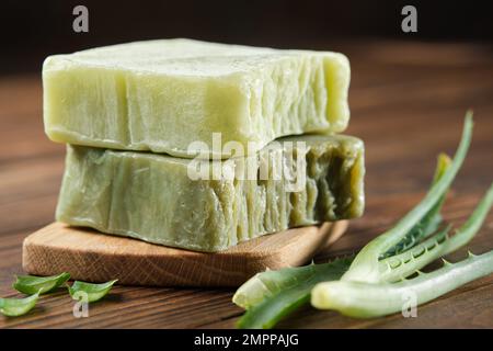 Barres de savon bio à l'aloe vera, savon naturel fait maison et feuilles d'aloès sur une planche en bois. Banque D'Images