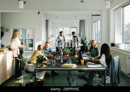 Des collègues d'affaires multiraciaux, hommes et femmes, communiquent entre eux au bureau Banque D'Images
