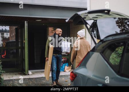 Homme transportant du carton et du contenant tout en parlant à la femme pendant le déplacement de la maison Banque D'Images