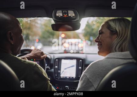 Heureux couple d'âge mûr qui parle les uns avec les autres en voyageant en voiture Banque D'Images