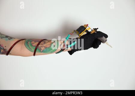 Tatouage artiste avec machine professionnelle sur fond blanc, gros plan Banque D'Images