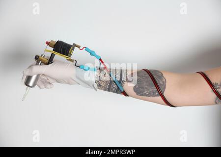 Tatouage artiste avec machine professionnelle sur fond blanc, gros plan Banque D'Images