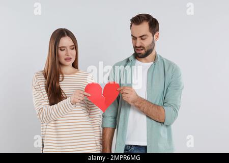 Couple déchirant le coeur de papier sur fond clair. Problèmes de relation Banque D'Images
