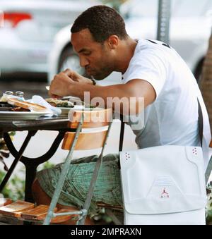 EXCLUSIF !! Craig David, chanteur britannique de R&B, est présent pour déjeuner dans un restaurant extérieur situé sur Lincoln Road avec un ami. Craig, dont le cinquième album studio signé Sealed livré est sorti en mars, s'est aidé à une assiette de nourriture partagée et s'est assis avec un sac Nike unique et sneaker, placé au-dessus de son épaule. Miami Beach, Floride. 08/29/10. Banque D'Images