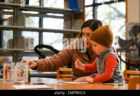 Un enfant et sa mère colorent un totem dans le cadre de la célébration du mois du patrimoine amérindien à la bibliothèque Bateman de la base conjointe Langley-Eustis, Virginie, le 16 novembre 2022. Les totems présentent les visages de personnes ou d'animaux ancestraux et ont été sculptés et peints par les Amérindiens du Nord-Ouest des États-Unis et du Canada pour démontrer leur importance religieuse, spirituelle ou sociale. Banque D'Images