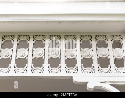 Les avant-toits en bois avec le pochoir de fleur sont décorés sur le bord de la maison locale, vue de face pour le fond. Banque D'Images