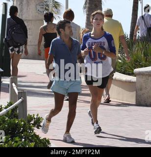 Jamel Debbouze et Melissa Theuriau vont faire un jogging. Les jambes de Debbouze montrent les cicatrices de son accident de voiture presque mortel en 1990. Miami, Floride. 2/27/09 Banque D'Images