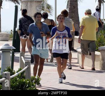 Jamel Debbouze et Melissa Theuriau vont faire un jogging. Les jambes de Debbouze montrent les cicatrices de son accident de voiture presque mortel en 1990. Miami, Floride. 2/27/09 Banque D'Images