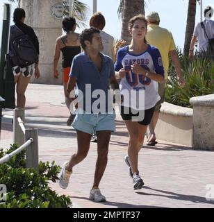 Jamel Debbouze et Melissa Theuriau vont faire un jogging. Les jambes de Debbouze montrent les cicatrices de son accident de voiture presque mortel en 1990. Miami, Floride. 2/27/09 Banque D'Images