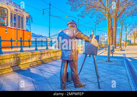 BUDAPEST, HONGRIE - 2 MARS 2022 : Promenade du Danube avec statue au peintre Ignac Roskovics et tramway jaune, sur 2 mars à Budapest Banque D'Images