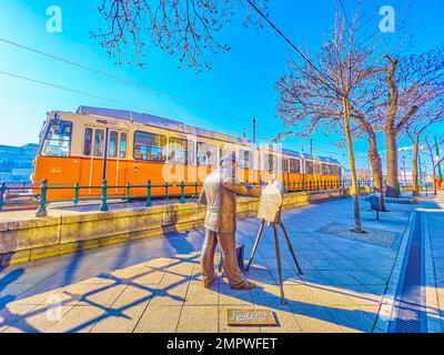 BUDAPEST, HONGRIE - 2 MARS 2022 : statue au peintre Ignac Roskovics et tramway rétro sur la promenade du Danube, sur 2 mars à Budapest Banque D'Images