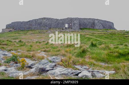 Deux touristes assis à l'extérieur de l'enceinte intérieure en pierre sèche de l'ancien fort de Dun Aengus sur Inishmore Aran Islands County Galway Irlande. Banque D'Images