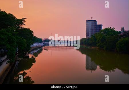 Le ciel de crépuscule se reflète sur les eaux calmes de la rivière Ping, entourée de végétation luxuriante sur les rives, Chiang Mai, Thaïlande Banque D'Images