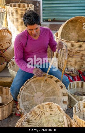 Un homme serpente des paniers en canne à vendre sur le marché d'Ocotlan de Morelos dans les vallées centrales d'Oaxaca, au Mexique. Banque D'Images