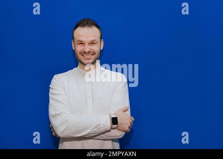 Positif et gai Guy aspect caucasien homme d'affaires élégant dans une chemise blanche sur un fond bleu. Banque D'Images