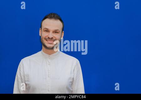 Positif et gai Guy aspect caucasien homme d'affaires élégant dans une chemise blanche sur un fond bleu. Banque D'Images