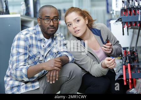 assistant de magasin de matériel africain amical aidant les jeunes couples à choisir des robinets Banque D'Images