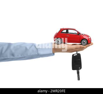 Homme tenant la clé et le modèle d'automobile miniature sur fond blanc, gros plan. Achat de voiture Banque D'Images