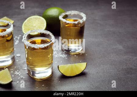 Prises de Tequila mexicaines, tranches de lime et sel sur table grise Banque D'Images