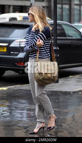 BBC radio 1 DJ Fearne Cotton prend un taxi à la maison après le travail au lieu de prendre sa promenade habituelle sur un vendredi pluvieux à Londres. Fearne, qui doit se rendre au Pérou pour une marche caritative la semaine prochaine, travaille une paire de talons aiguilles funky révélant le grand tatouage sur son pied, un chandail rayé et un pantalon gris. Londres, Royaume-Uni. 9/24/10. Banque D'Images