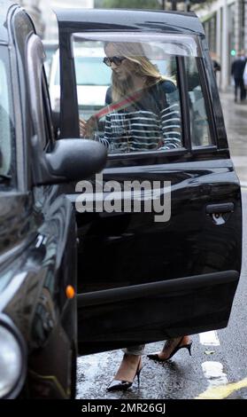 BBC radio 1 DJ Fearne Cotton prend un taxi à la maison après le travail au lieu de prendre sa promenade habituelle sur un vendredi pluvieux à Londres. Fearne, qui doit se rendre au Pérou pour une marche caritative la semaine prochaine, travaille une paire de talons aiguilles funky révélant le grand tatouage sur son pied, un chandail rayé et un pantalon gris. Londres, Royaume-Uni. 9/24/10. Banque D'Images