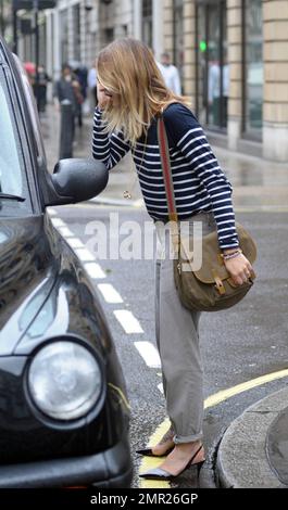 BBC radio 1 DJ Fearne Cotton prend un taxi à la maison après le travail au lieu de prendre sa promenade habituelle sur un vendredi pluvieux à Londres. Fearne, qui doit se rendre au Pérou pour une marche caritative la semaine prochaine, travaille une paire de talons aiguilles funky révélant le grand tatouage sur son pied, un chandail rayé et un pantalon gris. Londres, Royaume-Uni. 9/24/10. Banque D'Images