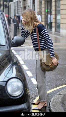 BBC radio 1 DJ Fearne Cotton prend un taxi à la maison après le travail au lieu de prendre sa promenade habituelle sur un vendredi pluvieux à Londres. Fearne, qui doit se rendre au Pérou pour une marche caritative la semaine prochaine, travaille une paire de talons aiguilles funky révélant le grand tatouage sur son pied, un chandail rayé et un pantalon gris. Londres, Royaume-Uni. 9/24/10. Banque D'Images