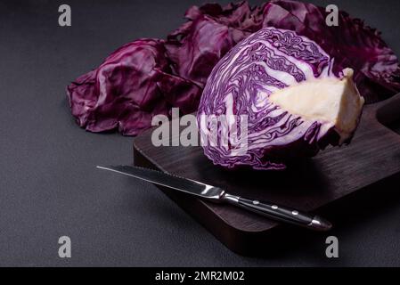 Beau chou rouge frais avec des feuilles texturées sur un fond en béton foncé. Cuisine végétarienne Banque D'Images