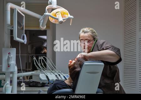 Kiev, Ukraine - 30 décembre 2022: Dentiste travaillant avec un patient dans un cabinet dentaire avec différents instruments et outils dentaires pour le traitement. Banque D'Images