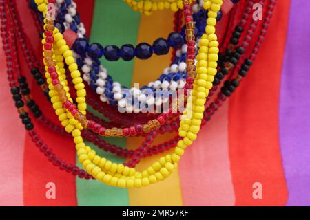 Jeu de perles de verre colorées accrochées devant un morceau de matériau coloré. Banque D'Images