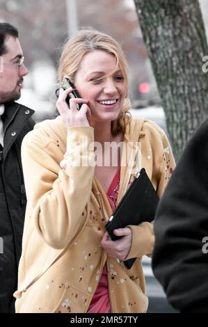 Blake Lively porte un confortable pull à capuche jaune sur une robe longue pêche et marche avec des gardes du corps entre les prises sur le plateau de la série télévisée CW « Gossip Girl » pendant le dernier jour de tournage de la saison. La plupart des stars étaient occupés à discuter sur leur téléphone portable, peut-être se préparer pour une fête de clôture amusante. New York, NY. 03/11/11. Banque D'Images