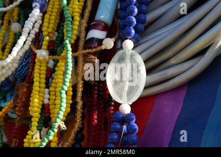 Gros plan de perles de verre colorées accrochées devant un matériau coloré. Banque D'Images