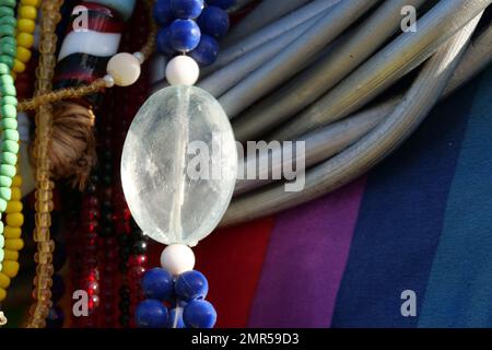 Gros plan de perles de verre colorées accrochées devant un matériau coloré. Banque D'Images