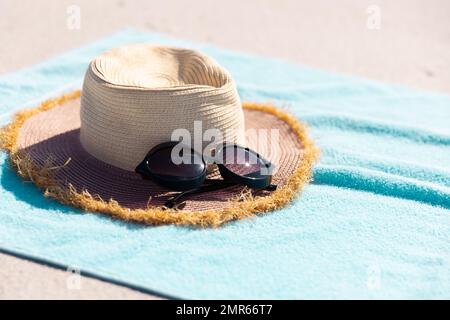 Gros plan de lunettes de soleil et chapeau sur une serviette bleue à la plage pendant la journée ensoleillée Banque D'Images