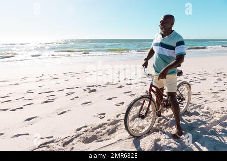 Image de l'homme afro-américain à vélo sur la plage par la mer Banque D'Images