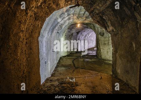 Tunnel voûté avec murs en béton dans un ancien bunker abandonné, mine, drainage, métro, etc Banque D'Images