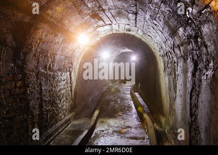 Tunnel voûté avec murs en béton dans un ancien bunker abandonné, mine, drainage, métro, etc Banque D'Images