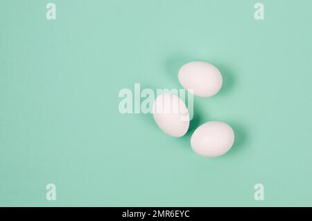 Gros plan sur les œufs de poulet blanc frais sur fond bleu. Groupe de trois œufs. Banque D'Images