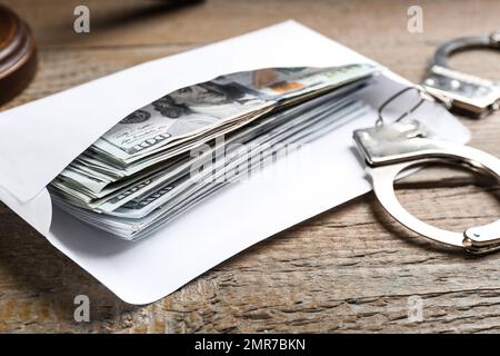 Billets et menottes en dollars sur une table en bois, gros plan. Concept de corruption Banque D'Images